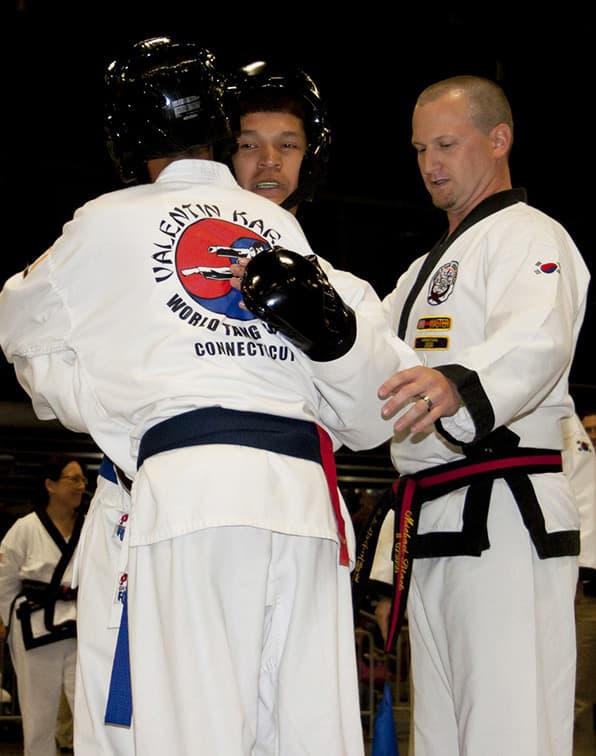A center judge standing between two competitors, checking in with them during a pause in the match.