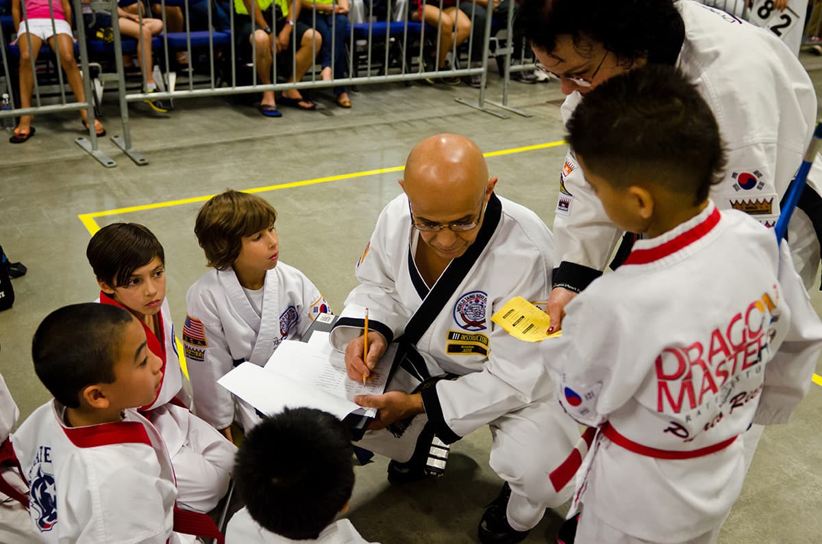A center judge reviewing a checklist with a group of young competitors before their matches.