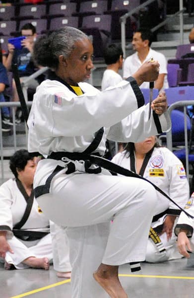 A competitor executing a high kick with a raised fist during a hyung performance.