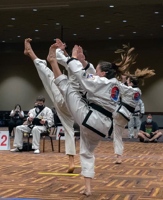 A team of competitors executing the same high kick at the same moment, in unison.